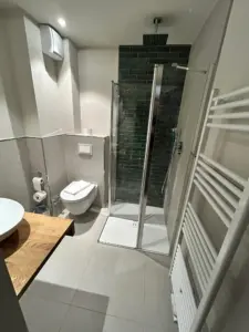 Modern saniertes kleines Badezimmer mit Dusche, WC und Waschtisch in grau-weißem Design
