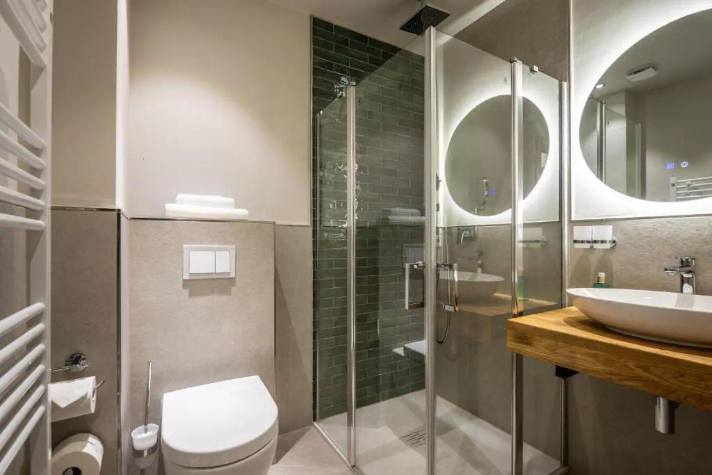 Modern saniertes Badezimmer mit Dusche, WC und Holzwaschtisch sowie LED-Spiegel