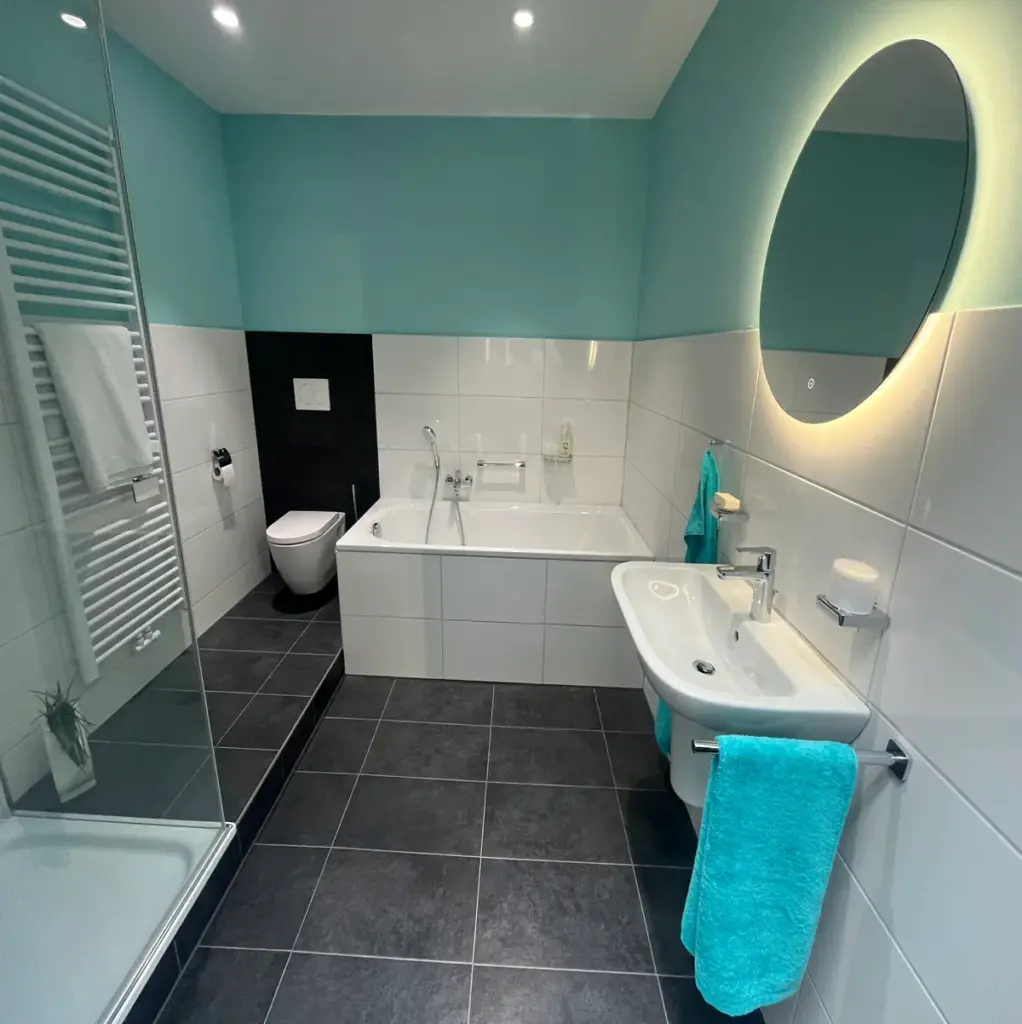 Modern saniertes Badezimmer mit Badewanne Dusche Waschbecken und LED Spiegel