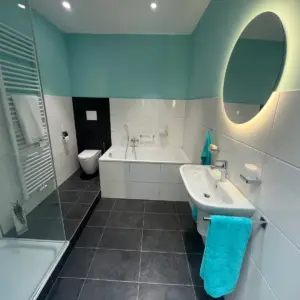 Modern saniertes Badezimmer mit Badewanne Dusche Waschbecken und LED Spiegel