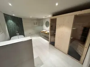 Modernes Luxusbad mit integrierter Sauna, freistehender Badewanne und großer Walk-in-Dusche