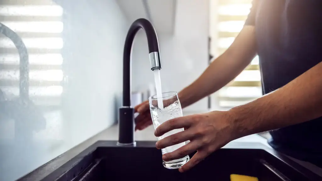 Sauberes Trinkwasser fließt aus Wasserhahn in Glas – moderne Trinkwasserinstallation im Haushalt