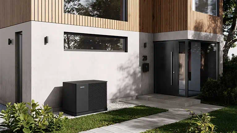 Außen aufgestellte Wärmepumpe an modernem Einfamilienhaus im Neubau